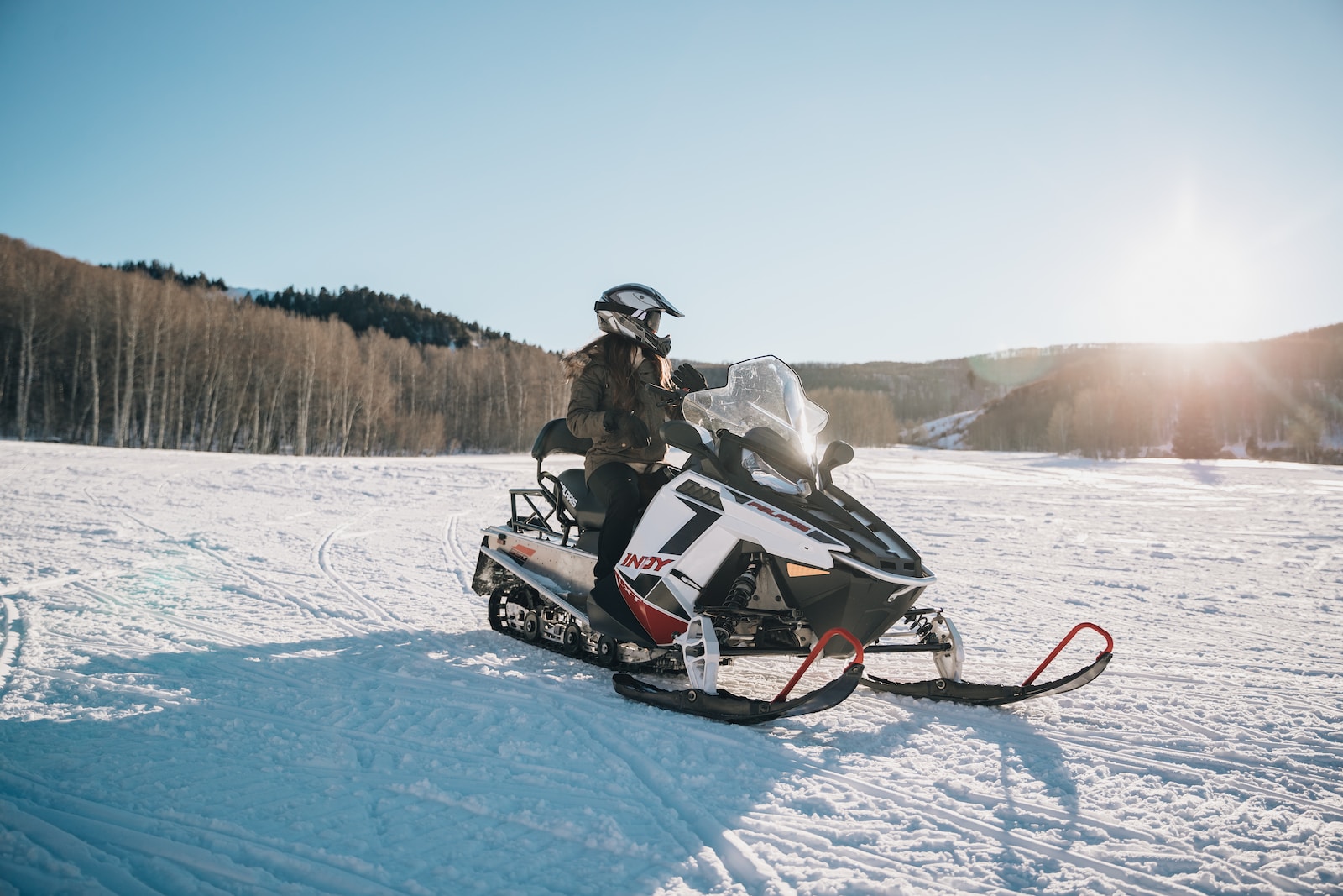 person riding on white and black snowmobile during daytime